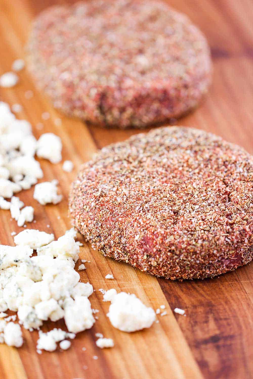 Uncooked sirloin burgers with blackening seasoning on them. 