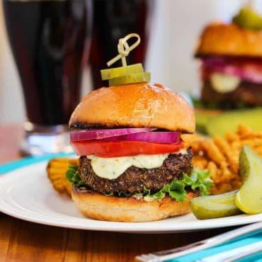 Rockin' Black and Bleu Burger on a white plate with a dark beer nearby.