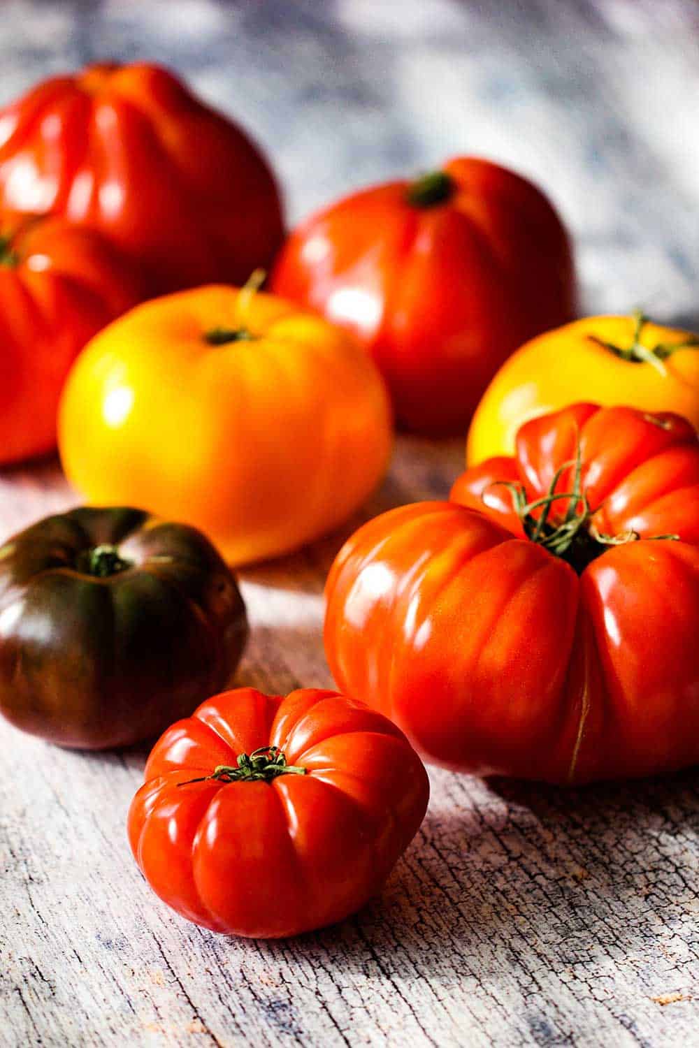 Heirloom tomatoes sitting on a wood plank 