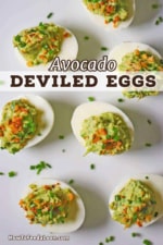 An overhead view of avocado deviled eggs that are arranged on a white platter that have been sprinkled with snipped chives and toasted breadcrumbs.