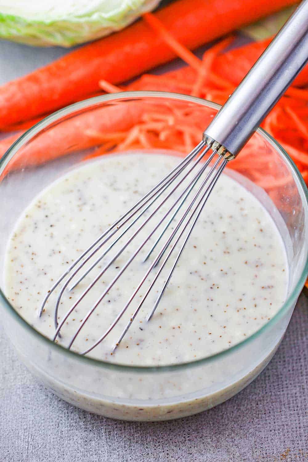 A creamy dressing with a whisk for coleslaw. 