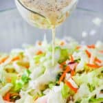 Dressing being poured onto homemade coleslaw.