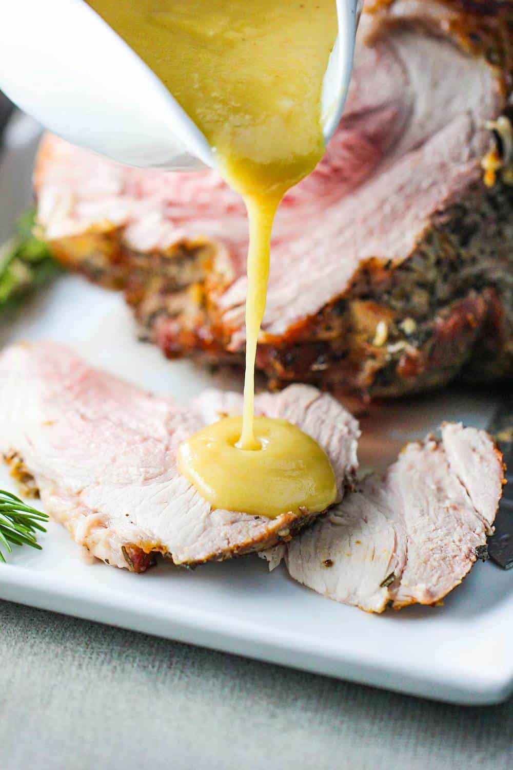 Pan gravy pouring onto a slow roasted pork shoulder