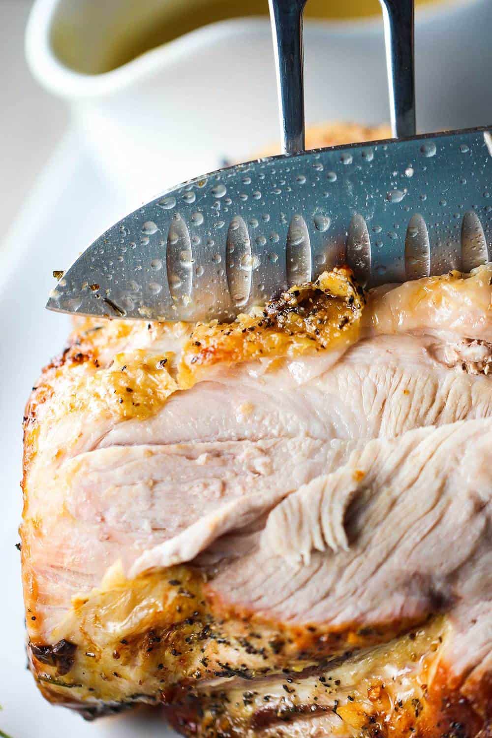 A knife and fork cutting a slow roasted pork shoulder