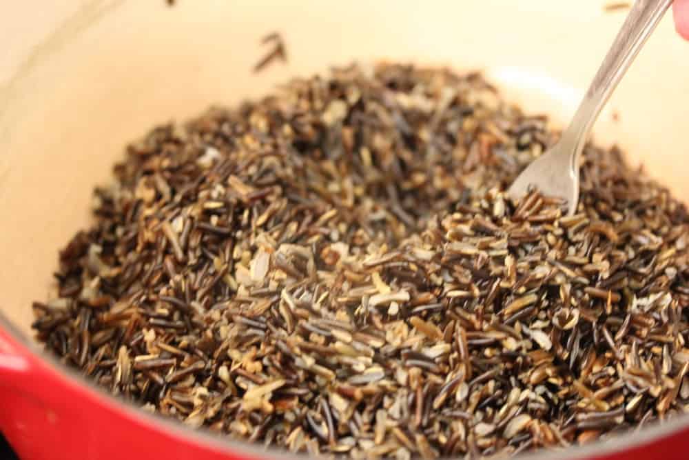 Wild rice cooked in a large pan with a fork