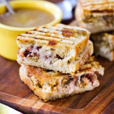 Day After Thanksgiving Panini and a bowl of gravy on a wooden cutting board