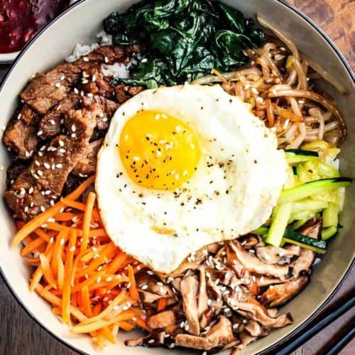 Authentic Bibimbap in a bowl with Korean BBQ sauce and chop sticks