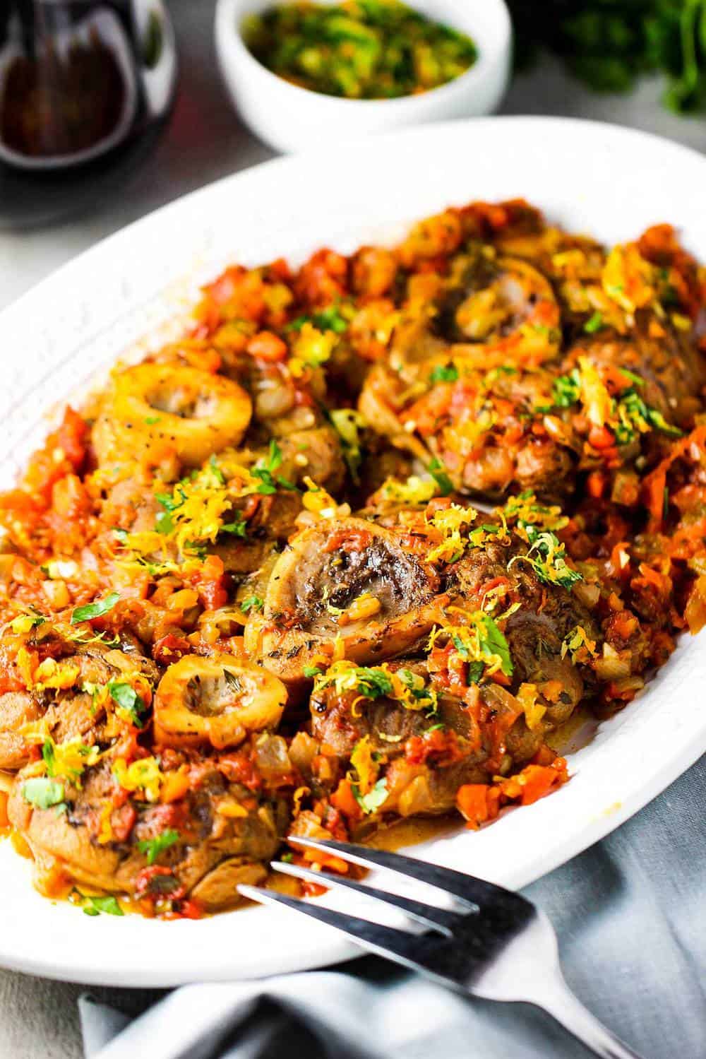 A white platter holding prepared authentic osso buco. 