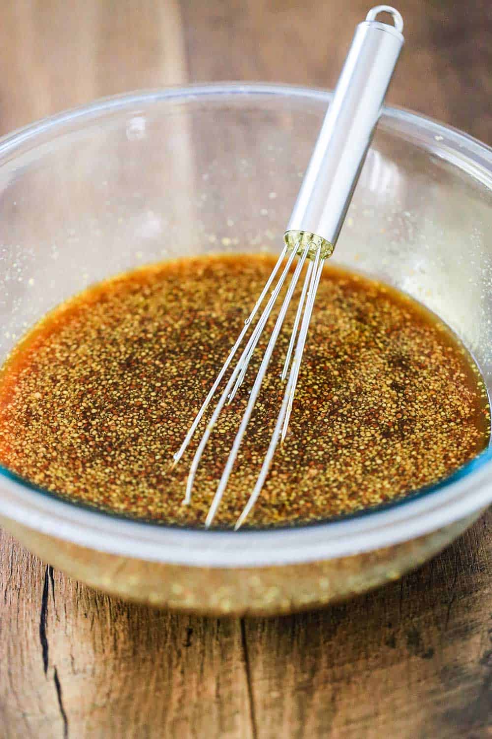 A glass bowl of honey bourbon glaze with a whisk in it. 