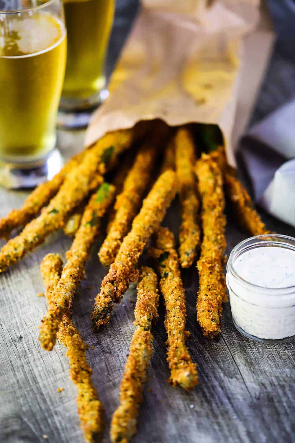 A pile of fried asparagus stalks pouring out of a paper bag.