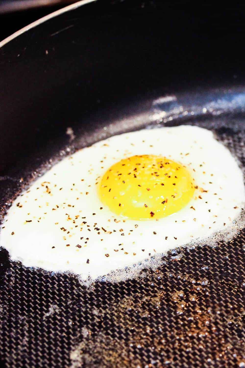 A sunny side up egg in a skillet for a Croque Madame