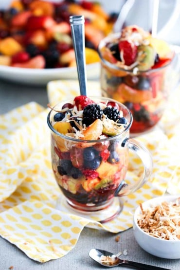 A large glass filled with summer fruit salad