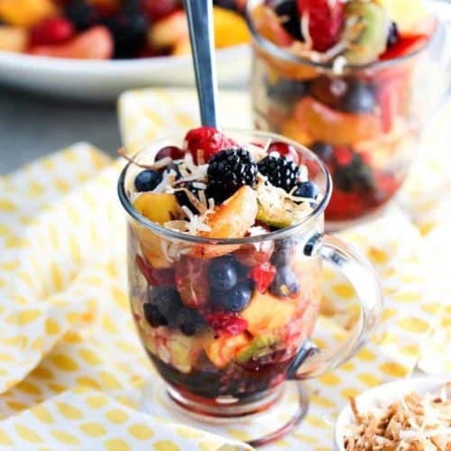 A large glass filled with summer fruit salad
