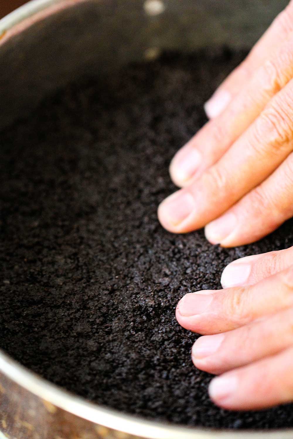 Use your hands to press the Oreo cookie crust into the base of the pan. 