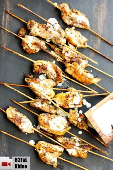 Grilled chicken on skewers with White Alabama Sauce dried over it.