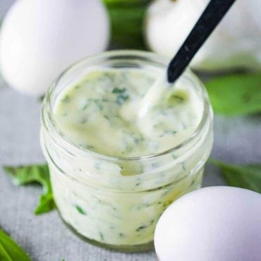 A small jar containing homemade garlic basil aioli with two eggs nearby.