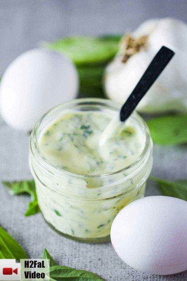 A small jar of garlic basil aioli with two eggs next to it.