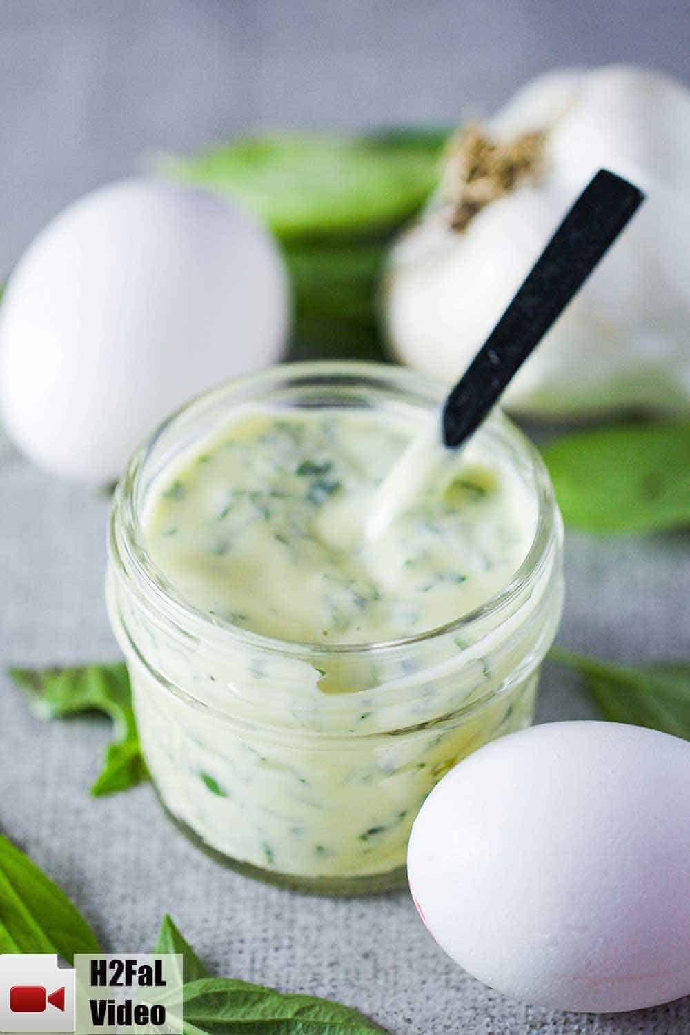 A small jar of garlic basil aioli with two eggs next to it. 