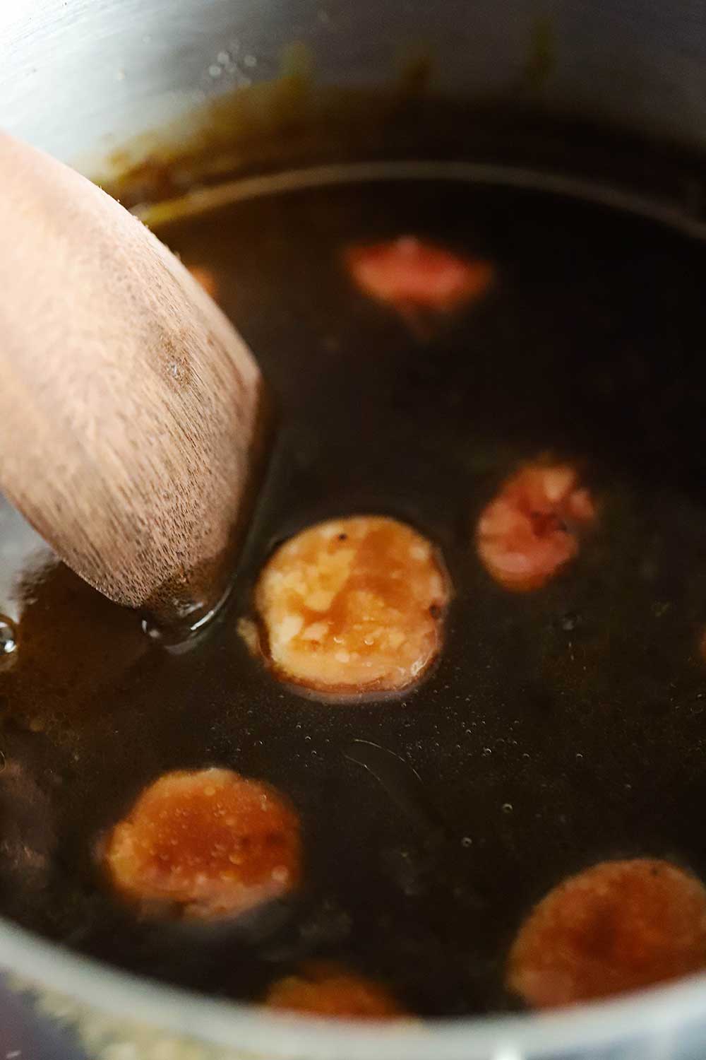 Slices of beef bone marrow sitting in a pan of simmering Bordelaise sauce. 