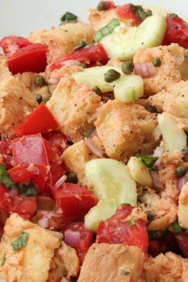 Panzanella (Bread and Tomato Salad) in a white bowl with a wood spoon