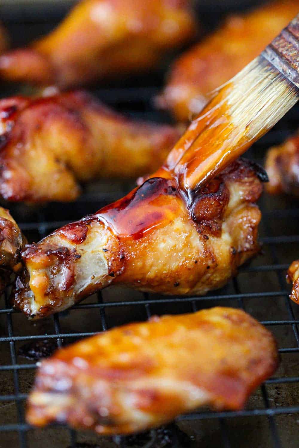 A brush adding a layer of teriyaki sauce to baked teriyaki chicken wings. 