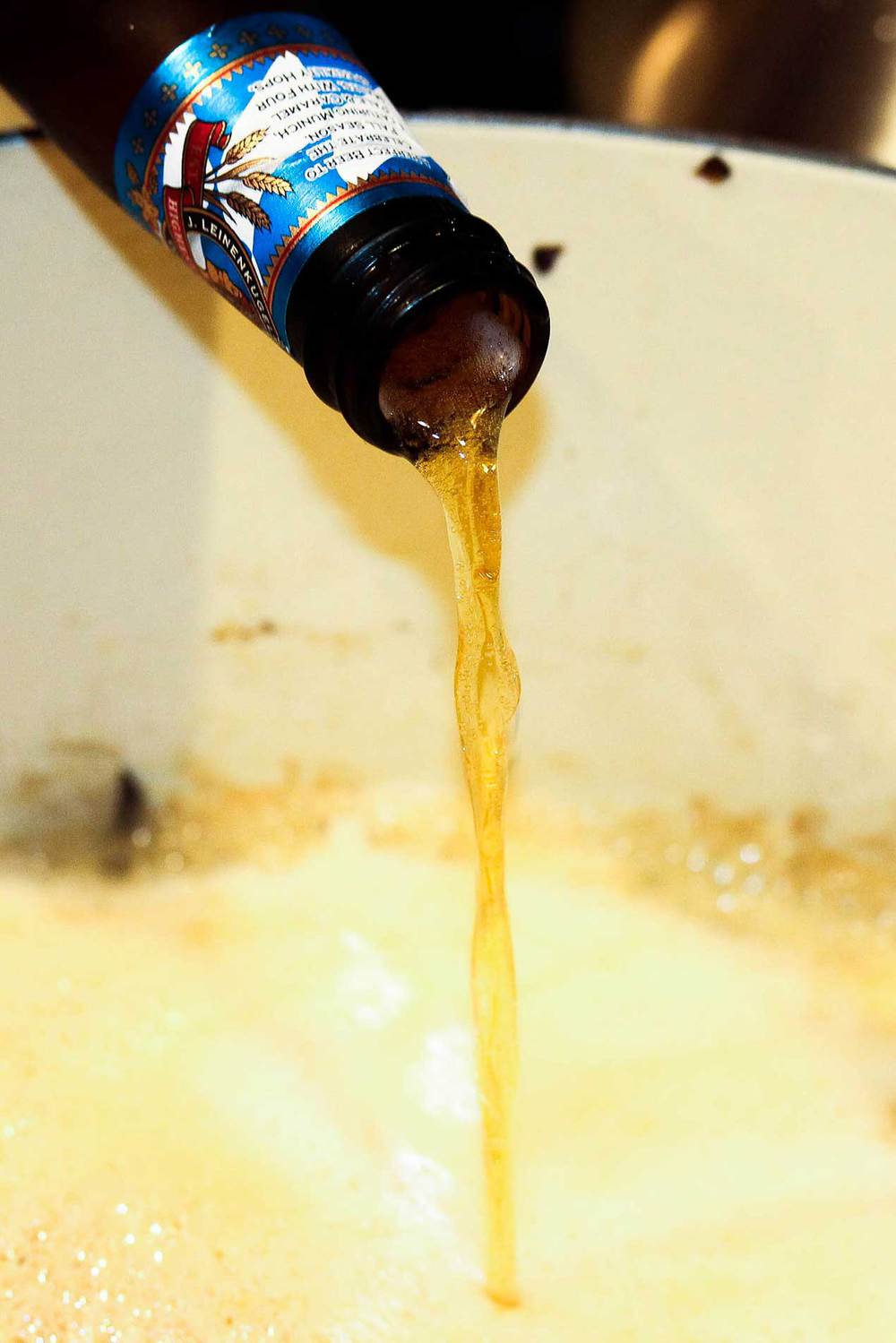 beer pouring into a Dutch oven for ale-braised bratwurst and sauerkraut