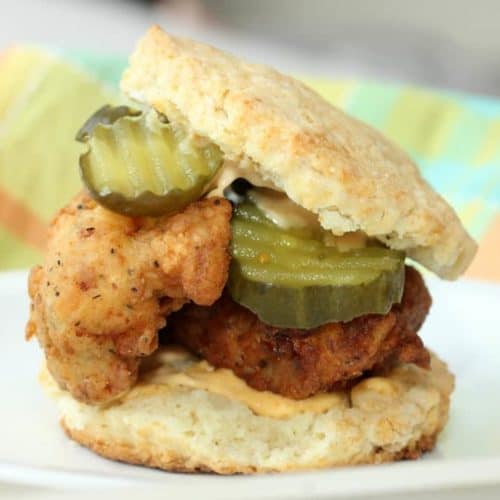 Fried Chicken and Buttermilk Biscuit Sandwich on a white plate next to a patterned napkin
