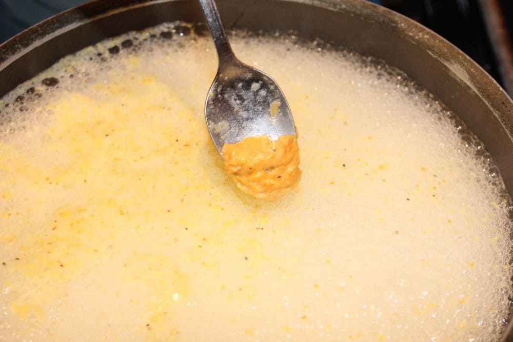 A spoon dropping dumplings into boiling water