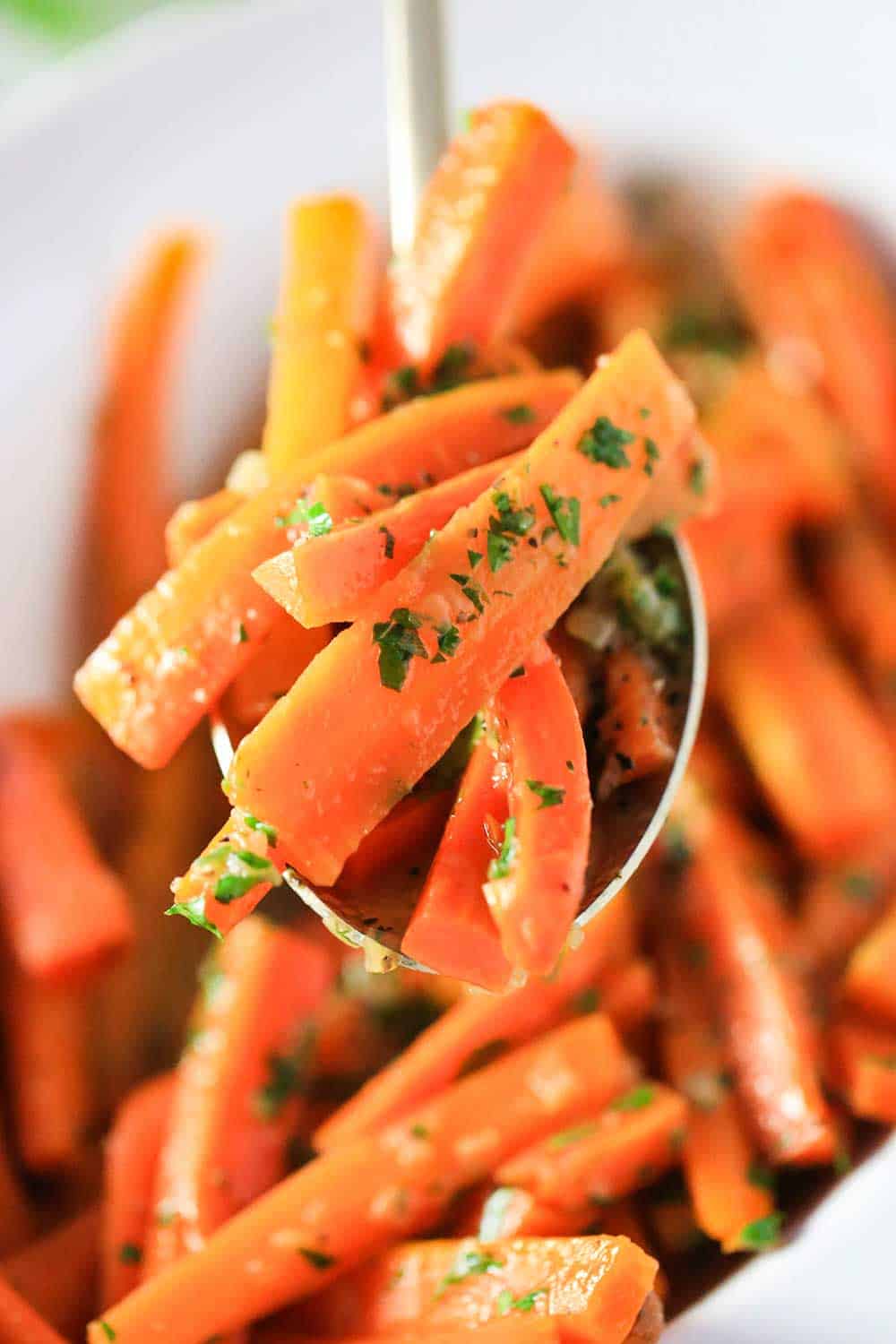 A spoon holding up a mound of maple braised carrots. 