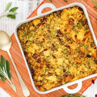 A square dish filled with cornbread dressing with sausage and cranberries.