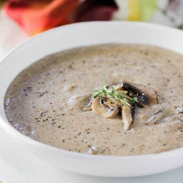 A close-up view of a white bowl holding cream of mushroom soup.