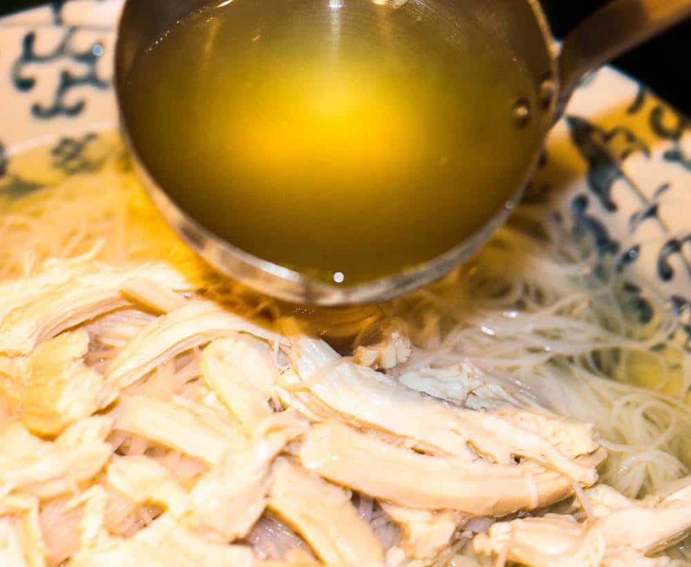 Chicken stock ladled into a bowl for chicken pho