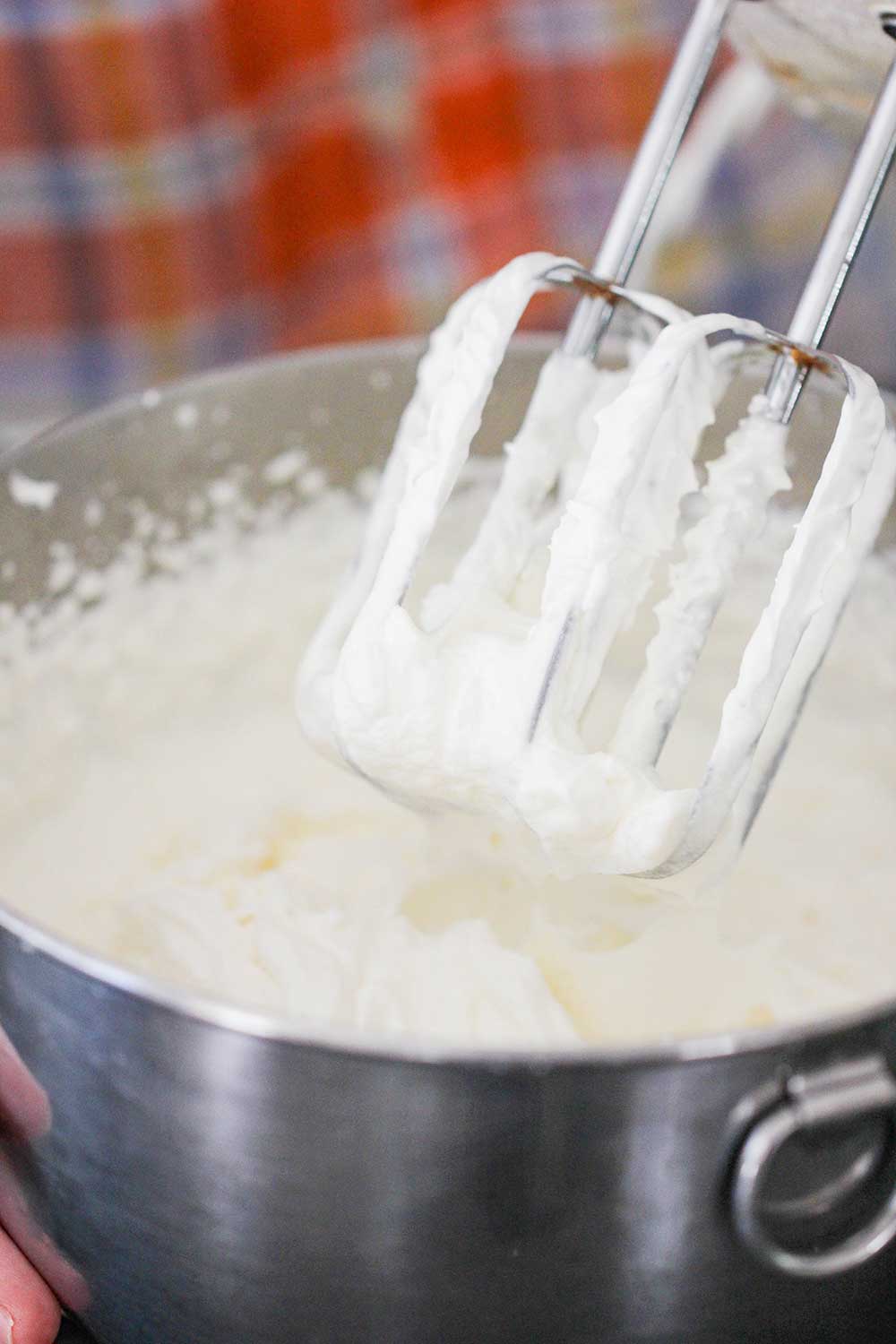 A mixer with whipped cream covering the attachments. 