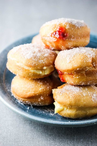 Jelly and custard doughnuts stacked on top of each other on a blue pattern plate.