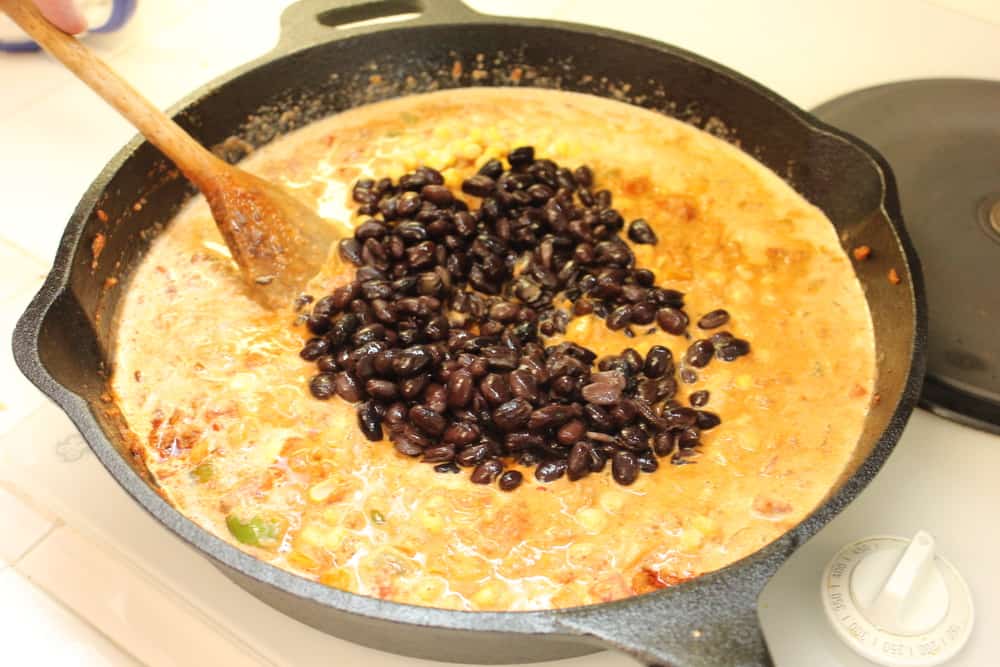 Cream, corn and beans in a cast iron skillet for Tex-Mex pasta