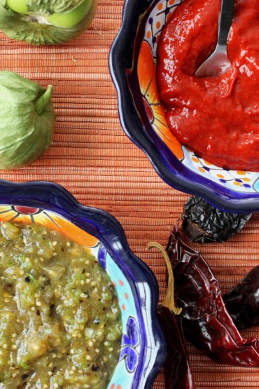 A bowl of roja salsa next to a bowl of roasted verde salsa