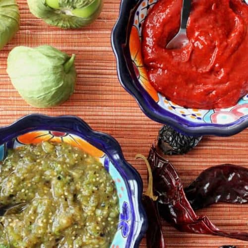 A bowl of roja salsa next to a bowl of roasted verde salsa