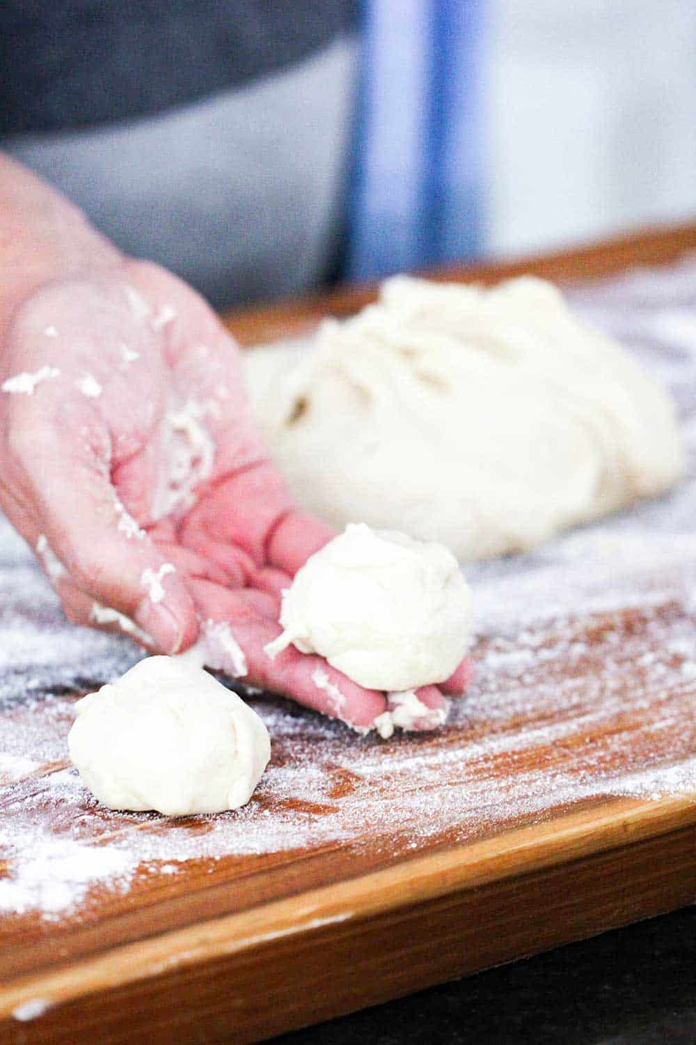 A hand holding a ball of dough for homemade flour tortillas. 