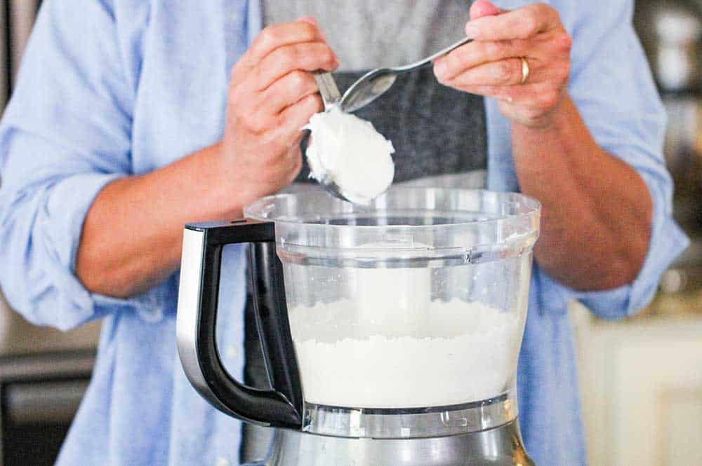 Lard being added into a food processor with other flour tortilla ingredients. 