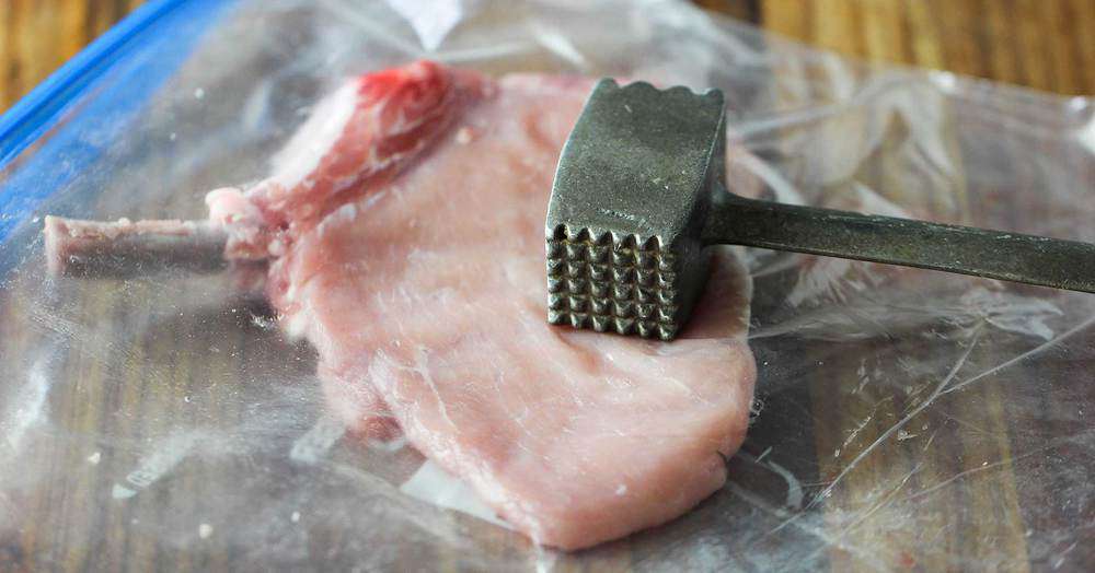 A center-cut pork chop in a plastic baggie with a meat mallet on top. 