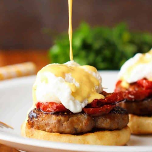 A white plate with Eggs Blackstone with Sausage being drizzled with hollandaise sauce