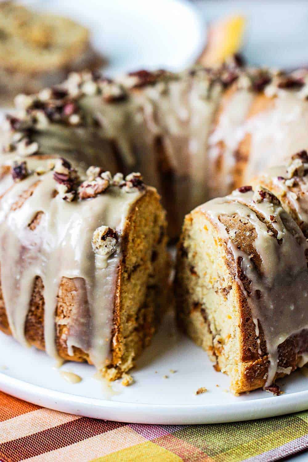 A sweet potato bundt cake on a white circular plate with a slice missing. 