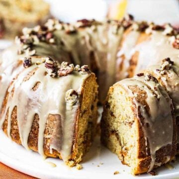 A sweet potato bundt cake on a white circular plate with a slice missing.
