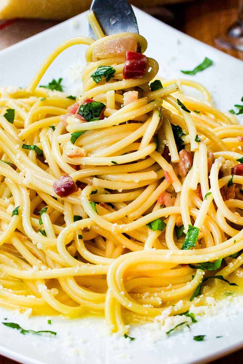 Twirl the pasta carbonara onto a plate with a fork. 