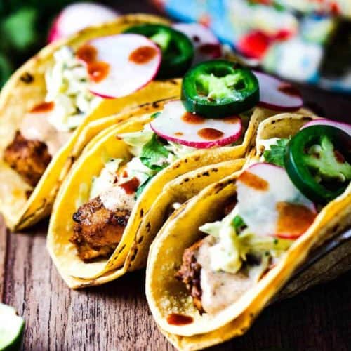 Mahi Mahi tacos in a taco rack on a wooden table.