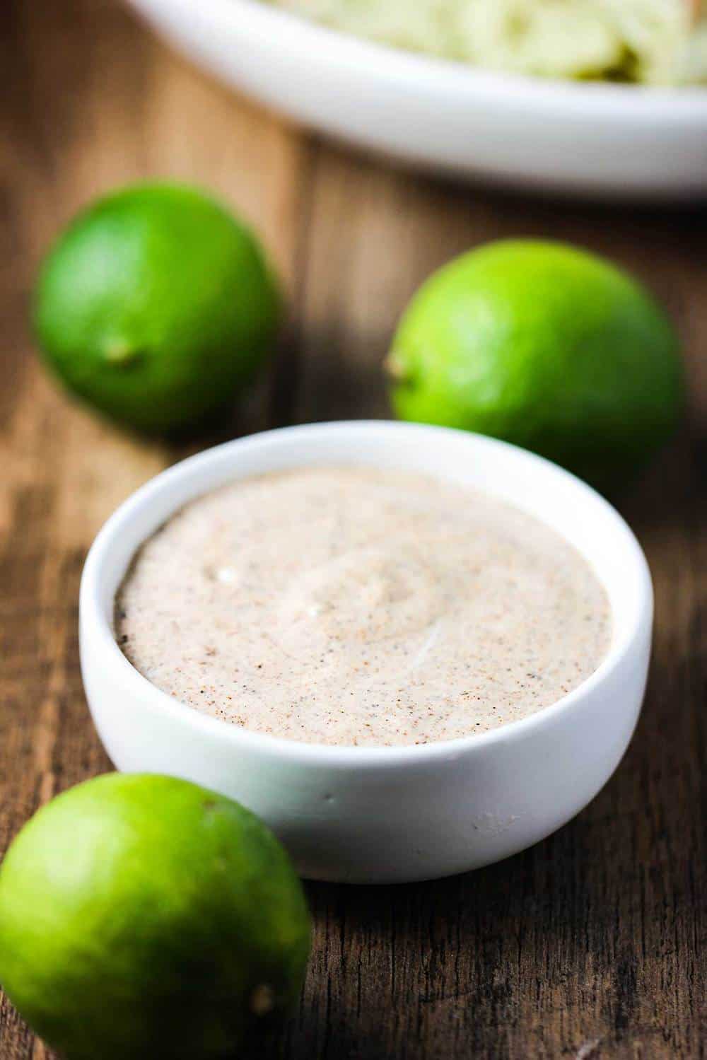 chipotle aioli in a white bowl with limes next to it. 