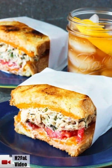 A blue plate with an amazing tuna melt next to a glass of iced tea