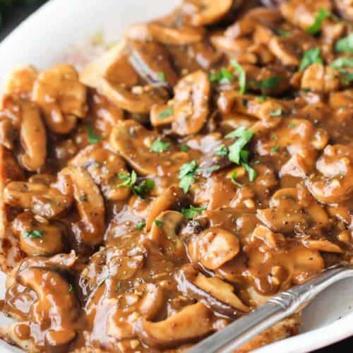 A white platter with Chicken Marsala