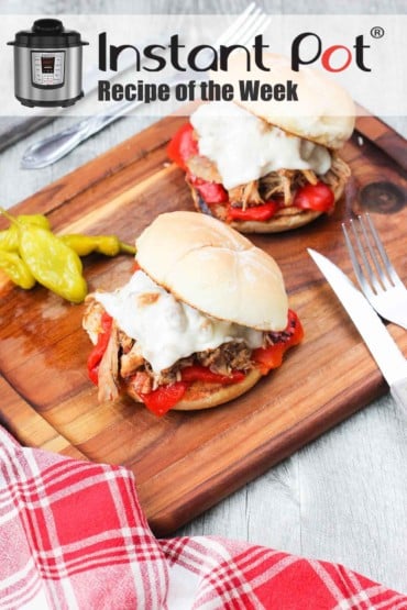 Instant Pot Italian Pulled Chicken Sandwich on a wooden cutting board with a knife and fork next to a patterned red napkin