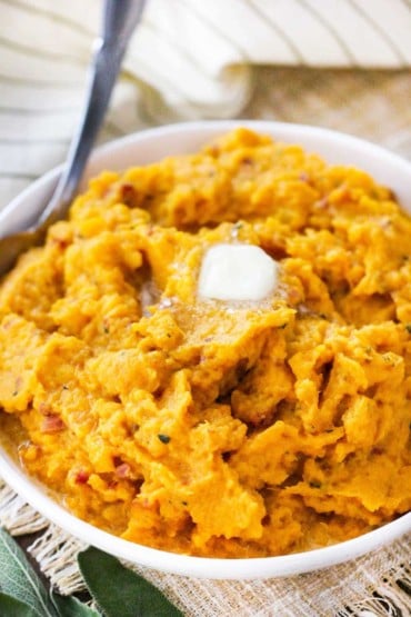 A white bowl holding pressure cooker mashed butternut squash with a tab of butter on top.